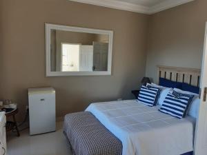 1 dormitorio con cama con almohadas azules y espejo en THE VIEW, en Port Alfred