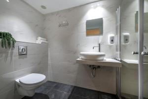a white bathroom with a toilet and a sink at Melio Hotel Eilat in Eilat