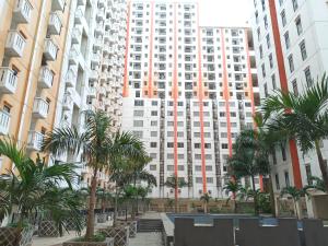 a tall building with palm trees in front of it at Adhigana Property Kemang View in Pekayon Satu