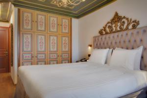a bedroom with a large white bed with a headboard at ARCHONTARIKI Historic Boutique Hotel in Ioannina