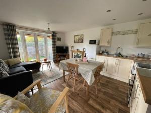 Chestnut Cottage في East Bergholt: مطبخ وغرفة معيشة مع طاولة وكراسي