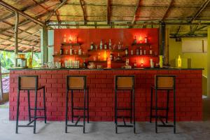 czerwony ceglany bar z trzema stołkami barowymi w obiekcie juSTa Morjim Beach Resort Goa - 80 Steps from Morjim Beach w mieście Morjim
