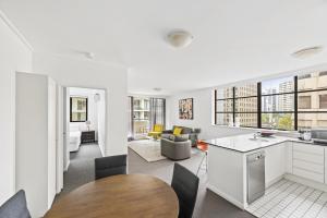 a kitchen and living room with white cabinets and a table at NAPI26N - Napier Vistas in Sydney