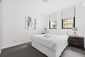 a white bedroom with a bed and two windows at NAPI26N - Napier Vistas in Sydney