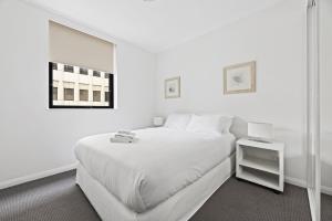 a white bedroom with a large bed and a mirror at NAPI26N - Napier Vistas in Sydney