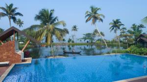 a swimming pool in front of a resort with palm trees at Gokulam Grand Resort & Spa, Kumarakom in Kumarakom