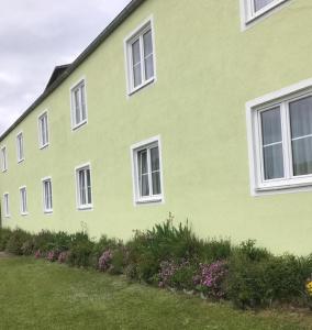 a green building with white windows and a yard at Landpension Gschwantner in Lengenfeld