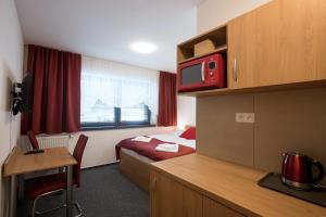 ein Hotelzimmer mit einem Bett, einem Schreibtisch und einem TV in der Unterkunft Vila DEDO in Tatranská Lomnica