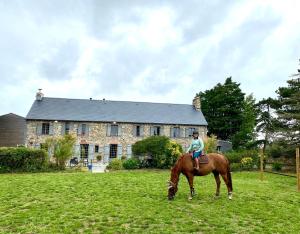 a person riding a horse in front of a house at Gite Ouest de la pointe d'Agon in Agon Coutainville