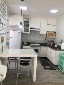 een keuken met witte kasten en een witte tafel bij Apartamento Peracanga com Wi-Fi in Guarapari