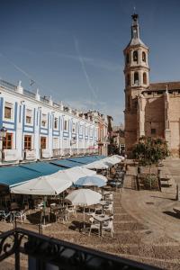 a group of tables and umbrellas in front of a building at Hospedium Aloque BOUTIQUE PLAZA in Valdepeñas