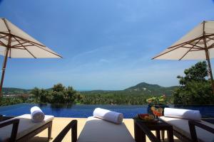 a swimming pool with two chairs and umbrellas at Villa Alpha - Seaview Private Villa in Choeng Mon Beach