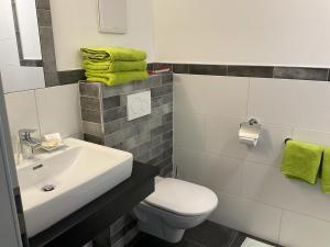ein Badezimmer mit einem Waschbecken, einem WC und grünen Handtüchern in der Unterkunft Göllerblick in Kernhof