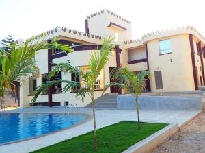 a house with a swimming pool in front of it at sunset suswa apartment in Mombasa