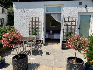 a patio with a table and chairs and flowers at Epchris House in Ilfracombe