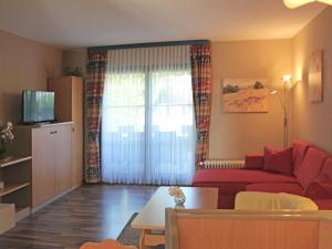 sala de estar con sofá rojo y ventana en Ferienhaus Nr 55, Kategorie Komfort, Feriendorf Hochbergle, Allgäu, en Karlsebene