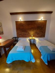 a bedroom with two beds and a brick wall at Casa do Páteo in Vila Nova da Baronia