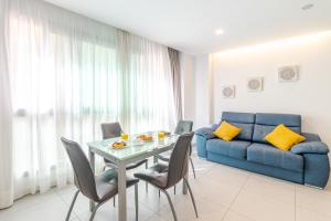 a living room with a table and a blue couch at Modern Flat Las Canteras in Las Palmas de Gran Canaria