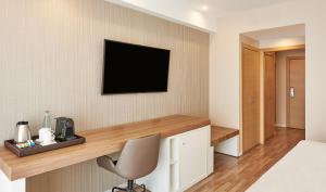 a room with a desk and a television on a wall at NH Andorra la Vella in Andorra la Vella