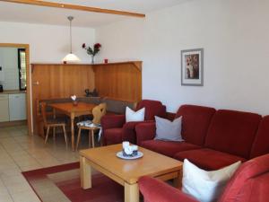 a living room with a red couch and a table at Ferienhaus Nr 93, Kategorie Komfort Plus, Feriendorf Hochbergle, Allgäu in Karlsebene