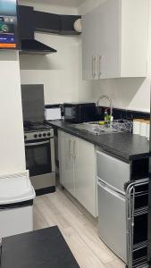 cocina con armarios blancos y encimera negra en BvApartments Queensgate 1, en Huddersfield