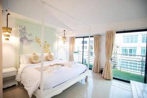 a bedroom with a white bed and a balcony at Nimman Mai Design Hotel Chiang Mai in Chiang Mai