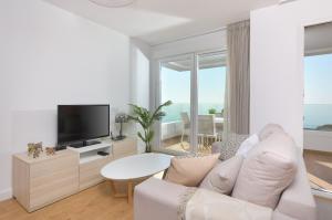 salon z białą kanapą i telewizorem w obiekcie Amplio apartamento vista mar frontal w mieście Torrox Costa