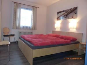 a bedroom with a bed with red sheets and a window at Ferienhaus Nr 96, Kategorie Premium, Feriendorf Hochbergle, Allgäu in Karlsebene