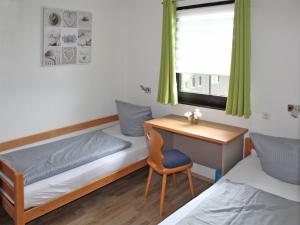 Cette chambre comprend un lit, un bureau, un lit et une chaise. dans l'établissement Ferienhaus Nr 62, Kategorie Premium, Feriendorf Hochbergle, Allgäu, à Bichel