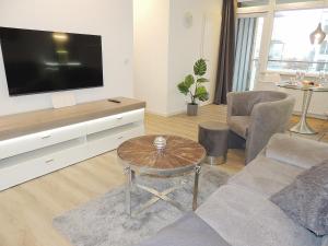 uma sala de estar com uma televisão, um sofá e uma mesa em Dünenhof DB1 011 Dünenhof em Heiligenhafen