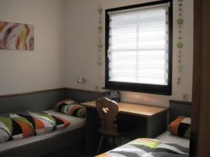 Zimmer mit 2 Betten, einem Schreibtisch und einem Fenster in der Unterkunft Ferienhaus Nr 137, Typ C, Feriendorf Hochbergle, Allgäu in Karlsebene