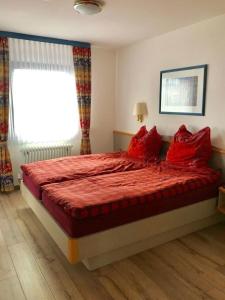 a bedroom with a large red bed with red pillows at Ferienhaus Nr 28, Kategorie Königscard, Feriendorf Hochbergle, Allgäu in Bichel