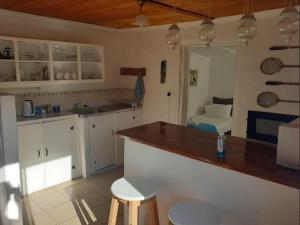 uma cozinha com armários brancos e um balcão com bancos em The Little Cottages em Howick