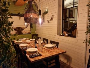 uma mesa de madeira com cadeiras e pratos e um lustre em Maison Zanella em Durbuy