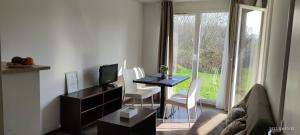 uma sala de estar com uma mesa e cadeiras e uma televisão em Appartement avec piscine près de Honfleur em Équemauville