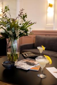 une table avec un vase de fleurs et deux verres à martini dans l'établissement Hotel Hamlet, à Elseneur
