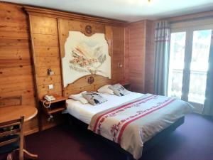 1 dormitorio con 1 cama con pared de madera en Epicéa Lodge Hôtel en Pralognan-la-Vanoise