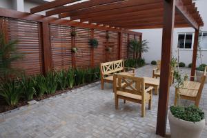 a patio with two benches and a wooden pergola at Hotel Plaza Cascavel in Cascavel