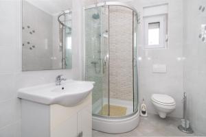uma casa de banho branca com um lavatório e um chuveiro em House Tatjana em Privlaka