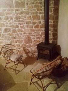 a brick fireplace with two chairs and a stove at La Thébaïde in Saint-Amour