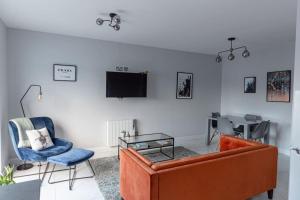 Causeway Coast Sea Front apartment - Ballycastle في باليكاسل: غرفة معيشة بها أريكة وكراسي وتلفزيون