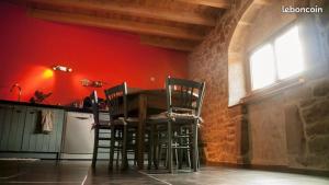 a table and chairs in a kitchen with a red wall at La Thébaïde in Saint-Amour