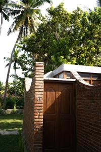 una recinzione di mattoni con un cancello in legno di fronte a una casa di The Spice Trail, Ahangama ad Ahangama