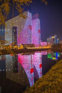 a city lit up at night with its reflection in the water at Orbi City Hotel Official in Batumi