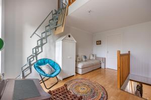 a living room with a blue chair and stairs at Maison L'Hippocampe in Saint-Aubin-sur-Mer