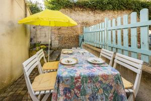 a table with a yellow umbrella on a patio at Maison L'Hippocampe in Saint-Aubin-sur-Mer