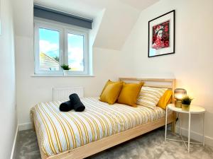 a bedroom with a bed with yellow pillows and a window at Stunning NEW Large 3 bedroom House - 5 Minutes to the nearest Beach! - Great Location - Garden - Parking - Fast WiFi - Smart TV - Newly decorated - sleeps up to 7! Close to Poole & Bournemouth & Sandbanks in Lytchett Minster