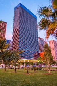 a tall building with palm trees in a park at Orbi Beach Tower Hotel Official in Batumi