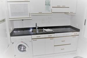 eine weiße Küche mit einem Waschbecken und einer Waschmaschine in der Unterkunft Vive Vitoria en la Almendra Medieval 15 in Vitoria-Gasteiz