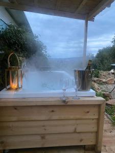 een hot tub met 2 wijnglazen op een tafel bij בית גלילי מול היער in ‘Ein Ya‘aqov
